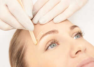 Woman having an eyebrow wax treatment